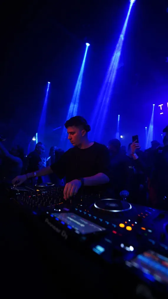 Aftermovie frame, DJ under blue light beams