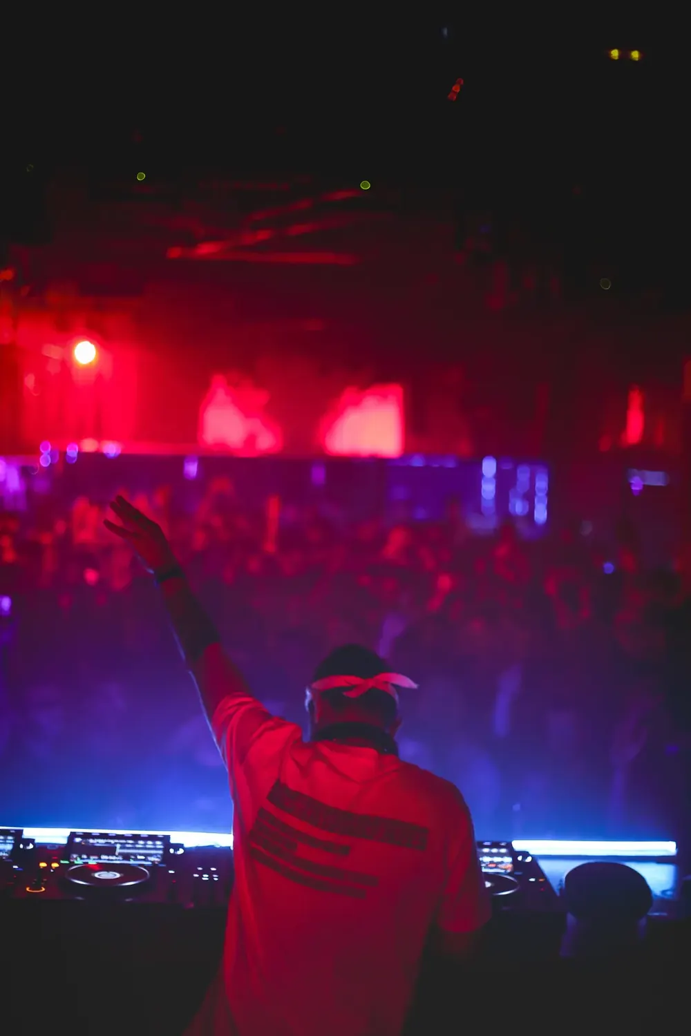 DJ with arm raised, red and blue light