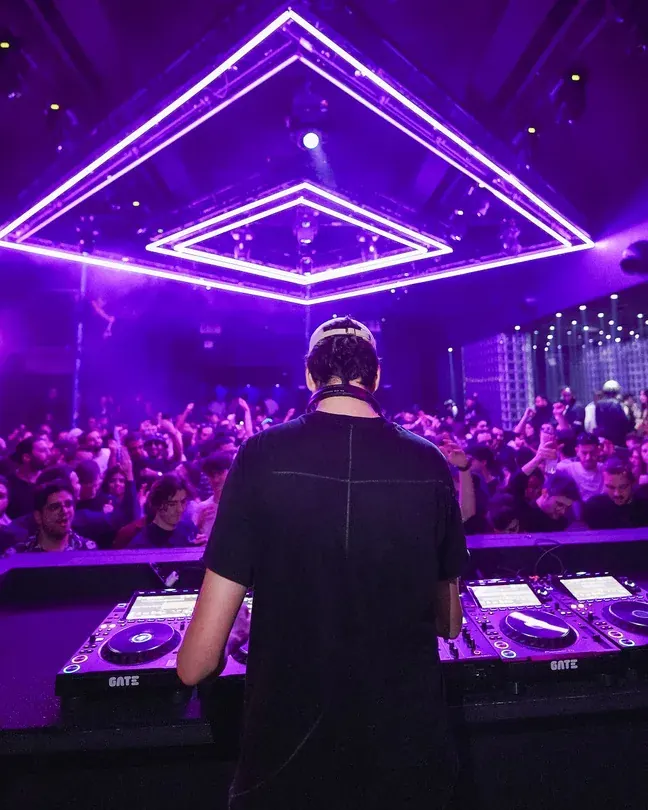DJ behind the decks under violet diamond lights at Gate